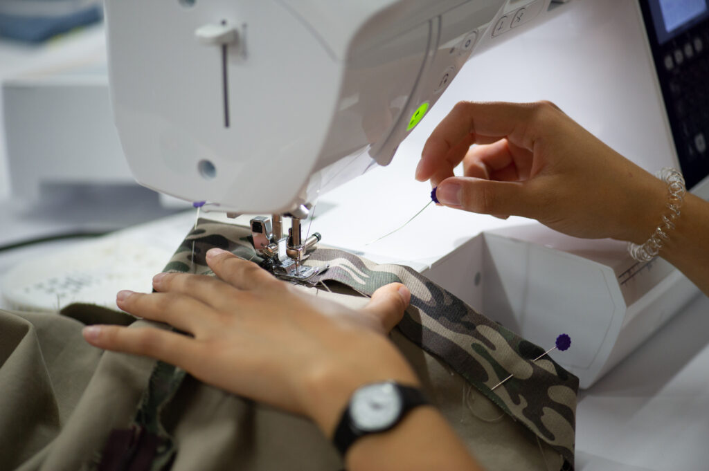 A Sewing student working on sewing a hem on a twill fabric using a sewing machine